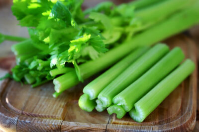 elery sticks on a wooden board. Fresh celery leaves.