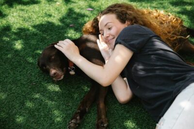 Smiling woman caressing hunting dog while resting on meadow