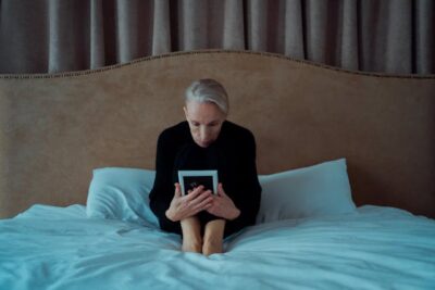 Elderly Woman Sitting on Bed Looking at a Picture Frame