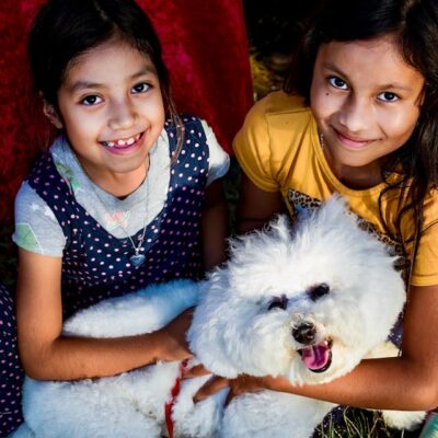 Girls Carrying White Bichon Frise while Smiling at the Camera